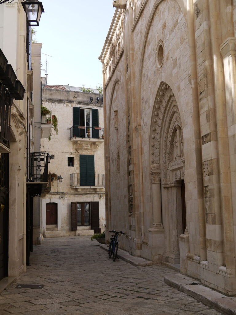 Along the side of the cathedral, Conversano: portal and bicycle