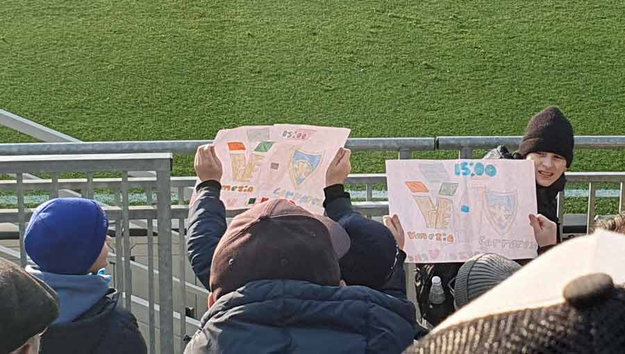 Young fans holding up match day artwork